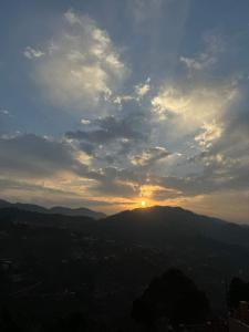 a view of the sun setting over a mountain at Sun Rise View at Twin Oaks' in Kasauli