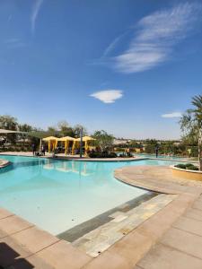 a large swimming pool with blue water and yellow umbrellas at Trilogy Polo Club - Casita in Indio