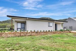 a white house with a stone wall at Somerville Wines Lux Escape 3-Bedroom Cottage Near Broke Wineries in Broke