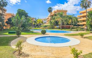 a swimming pool in a park with palm trees and a building at Awesome Apartment In La Cala De Mijas With House A Mountain View in La Cala de Mijas