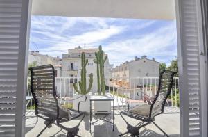 einen Balkon mit 2 Stühlen, einem Tisch und einem Kaktus in der Unterkunft The Luxor Apartment by Hello Homes Sitges in Sitges