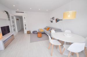ein weißes Wohnzimmer mit einem Tisch und einem Sofa in der Unterkunft The Luxor Apartment by Hello Homes Sitges in Sitges
