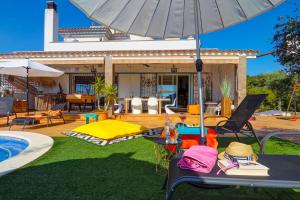 - une terrasse avec des tables et un parasol à côté de la piscine dans l'établissement Villa Talaya by Hello Homes Sitges, à Sant Pere de Ribes