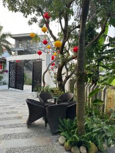 eine Terrasse mit Stühlen und einem Tisch unter einem Baum in der Unterkunft Water Palm Residence in Hiếu Nhơn