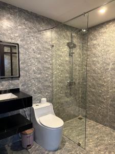 La salle de bains est pourvue de toilettes et d'une douche en verre. dans l'établissement Water Palm Residence, à Hiếu Nhơn