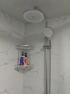 a shower in a bathroom with white marble walls at Shanghai Garden Apartment - Near Downtown Wukang Road in Shanghai