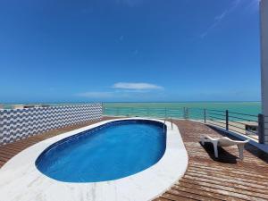 a swimming pool on a deck with the ocean in the background at Edifício Monte Sinai in Cabedelo