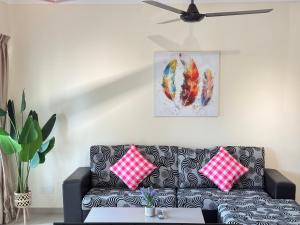 a living room with a black couch with red and white pillows at Desaru Private Beach Family Suite Big Pool D0513 in Bandar Penawar