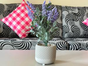 a white vase with purple flowers on a table at Desaru Private Beach Family Suite Big Pool D0513 in Bandar Penawar