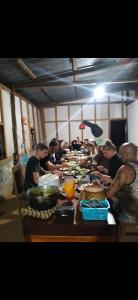 eine Gruppe von Menschen, die an einem Tisch mit Essen sitzen in der Unterkunft Shared Happy Farm in Ban Nongboua