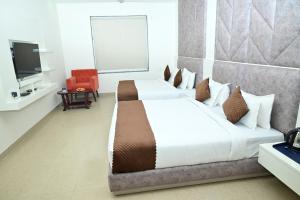 a hotel room with two beds and a television at Click Hotel Narayana in Ayodhya