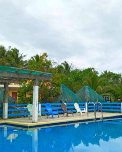 a group of blue benches next to a swimming pool at Lotus Sun & Waves Beach Resort in Baler