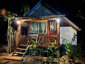 a small house with a ladder and a chair in front at Baan rabiang Pai บ้านระเบียงปาย in Pai