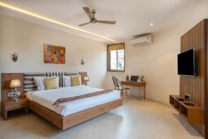 a bedroom with a bed and a flat screen tv at StayVista's Tree House at Sula Wada - Cozy Home with Vintage Charm, Swimming Pool, Indoor Activities in Panchgani