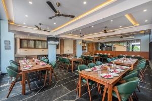 a restaurant with wooden tables and green chairs at StayVista's Tree House at Sula Wada - Cozy Home with Vintage Charm, Swimming Pool, Indoor Activities in Panchgani