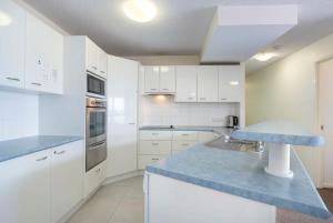 eine Küche mit weißen Schränken und einer blauen Arbeitsplatte in der Unterkunft Sunny 'Beachside' Unit Buddina Resort in Buddina