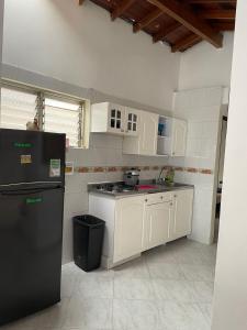 uma cozinha com armários brancos e um frigorífico preto em Casa cómoda y amplia en laureles em Medellín