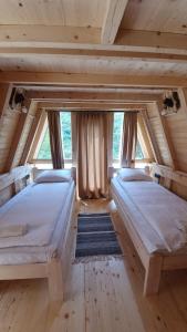 two beds in a room with wooden floors and windows at Rajska Rijeka in Foča