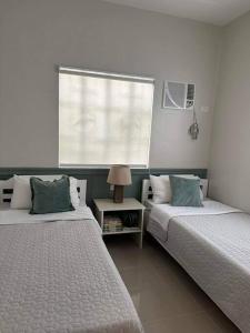 a bedroom with two beds and a window and a table at Japandi Home A - Fully Aircon, WIFI, Hot shower, 24hGuard, Center, near Malls in General Santos