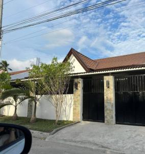 a house with two black garage doors and trees at Japandi Home A - Fully Aircon, WIFI, Hot shower, 24hGuard, Center, near Malls in General Santos