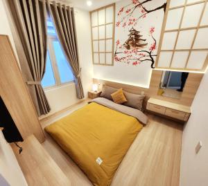 a bedroom with a bed with a yellow blanket at Ohayou Dalat Homestay in Da Lat