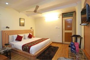 een slaapkamer met een groot bed en een televisie bij Goroomgo Moon Nainital Near Naini Lake - Parking & Lift Facilities -Hygiene and Spacious Room - Best Seller in Nainital