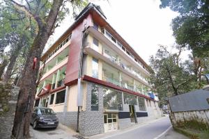 a building with a car parked in front of it at Goroomgo Moon Nainital Near Naini Lake - Parking & Lift Facilities -Hygiene and Spacious Room - Best Seller in Nainital