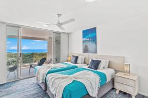 a bedroom with two beds and a balcony at Coral View at Azure Sea in Airlie Beach