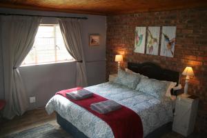 a bedroom with a bed and a brick wall at Suikerbosskuur Rondavel & Chalet in Amsterdam