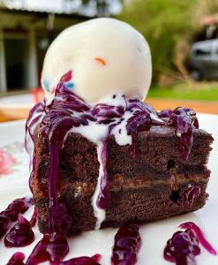 un trozo de pastel de chocolate con glaseado blanco y púrpura en Hotel Campestre Finca el Carriel - Quindío - Eje Cafetero, en Montenegro