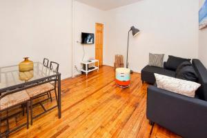 uma sala de estar com um sofá preto e um piso de madeira em 102-2A Specious 2BR Best Value Near Cntrl Park em Nova York