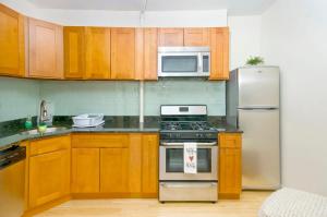 a kitchen with wooden cabinets and stainless steel appliances at 102-1A Best Value 2BR Apt Near Central Park in New York