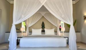 a bedroom with a white bed with a canopy at Meno House - Adults Only in Gili Meno