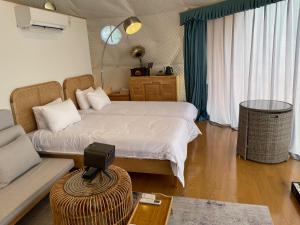 山中湖村にあるGramercy Village 山中湖 Glamping &Saunaのベッドルーム1室(ベッド2台、ソファ、テーブル付)