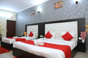 a bedroom with two beds with red and white pillows at Hotel Global Inn By Quality Inn in New Delhi