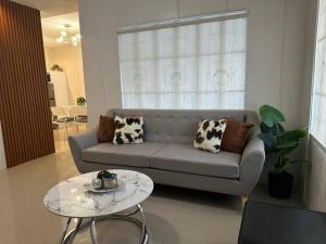 ein Wohnzimmer mit einem Sofa und einem Tisch in der Unterkunft Japandi Home B - Fully Aircon, WIFI, Hot shower, 24hGuard, Center, near Malls in General Santos