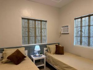 dwa łóżka w pokoju z dwoma oknami w obiekcie Japandi Home B - Fully Aircon, WIFI, Hot shower, 24hGuard, Center, near Malls w mieście General Santos