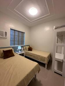 Cette chambre comprend 2 lits et une fenêtre. dans l'établissement Japandi Home B - Fully Aircon, WIFI, Hot shower, 24hGuard, Center, near Malls, à General Santos