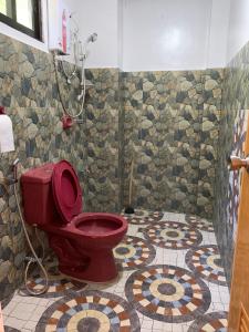 a bathroom with a red toilet and a mosaic floor at Lotus Sun & Waves Beach Resort in Baler