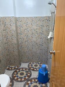 a bathroom with a toilet and a tiled floor at Lotus Sun & Waves Beach Resort in Baler