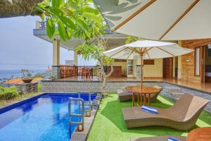 a pool with chairs and a table and an umbrella at Penida La Casa Cottage in Nusa Penida