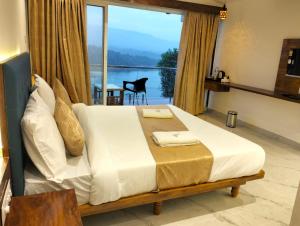 a bedroom with a bed and a large window at Nisarga Lake Resort in Satara