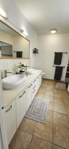 a bathroom with two sinks and a mirror at House in a private residential area in Paea