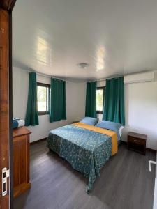 Parea的住宿－Parea Lodge Huahine BUNGALOW F2 #Miti，一间卧室配有一张带绿色窗帘的床