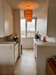 a kitchen with white cabinets and a large window at Appartement Sainte-Cécile in De Panne