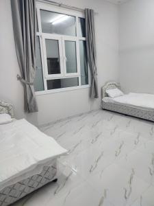 a bedroom with white marble floors and a window at Jabal Shams, Al Noor house جبل شمس in Misfāh