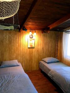 two beds in a room with wooden walls and a window at Будинки рибалки in Sudovaya Vishnya