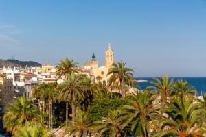 Elle offre une vue sur une ville bordée de palmiers et l'océan. dans l'établissement Charming House by Hello Homes Sitges, à Sitges