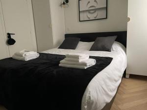 um quarto com uma cama preta e branca com toalhas em Élégant Appartement près du Musée du Louvre et du Jardin des Tuileries em Paris