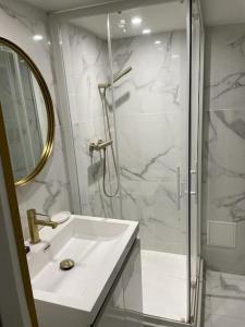 uma casa de banho branca com um chuveiro e um lavatório. em Élégant Appartement près du Musée du Louvre et du Jardin des Tuileries em Paris